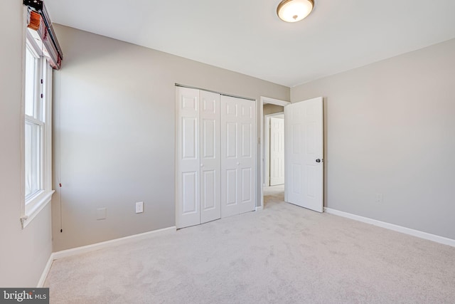 unfurnished bedroom featuring light colored carpet, multiple windows, and baseboards