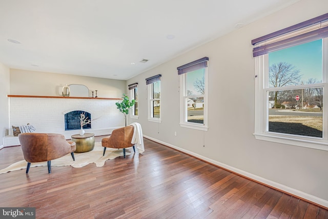 living area featuring visible vents, a fireplace, baseboards, and wood finished floors