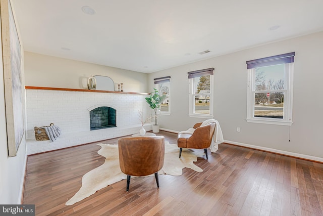 living area with a brick fireplace, wood finished floors, and baseboards