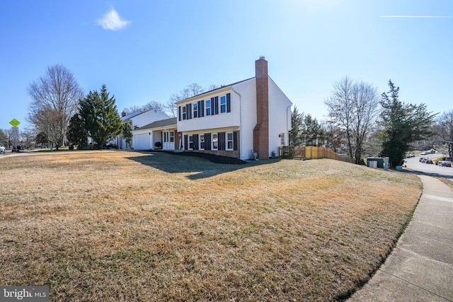 view of front facade with a garage, a chimney, fence, and a front yard