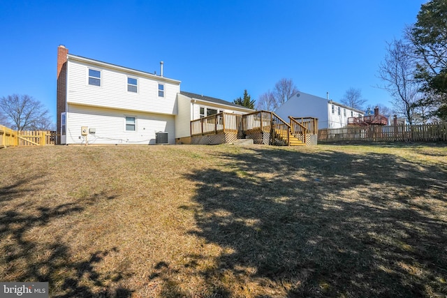 rear view of house with a lawn, cooling unit, a wooden deck, and fence