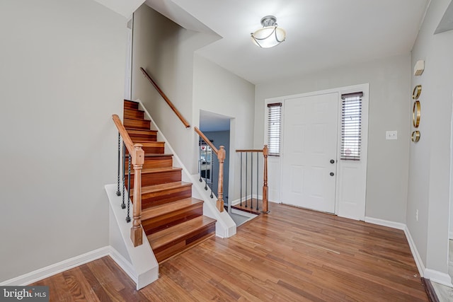 foyer featuring light wood-style flooring, stairs, and baseboards