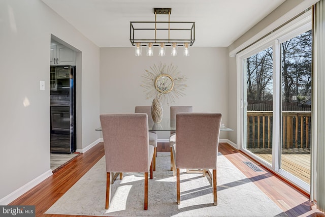 dining space featuring light wood-type flooring, visible vents, and baseboards