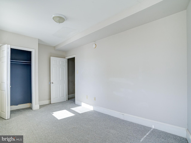 unfurnished bedroom with light carpet and a closet