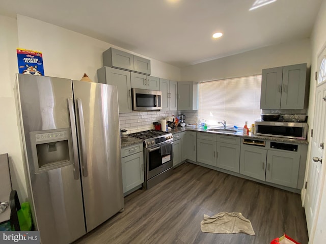 kitchen featuring appliances with stainless steel finishes, dark hardwood / wood-style flooring, sink, and decorative backsplash