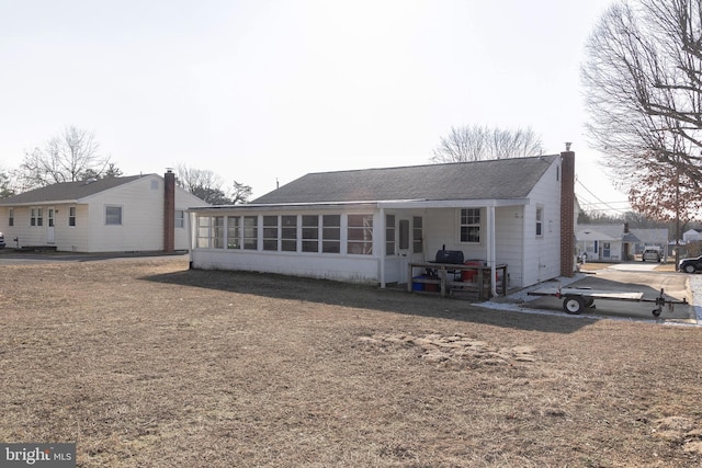 back of property with a sunroom and a lawn