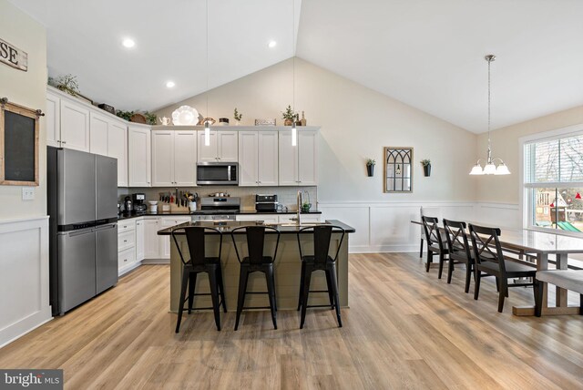 kitchen featuring white cabinetry, stainless steel appliances, a breakfast bar area, and pendant lighting