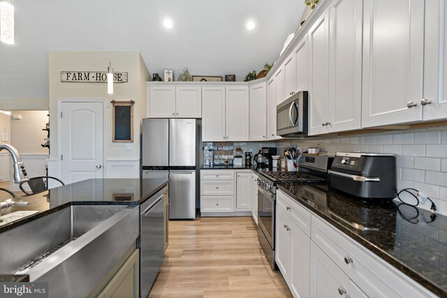 kitchen featuring appliances with stainless steel finishes, white cabinets, and decorative light fixtures