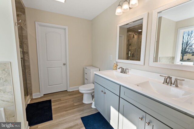 bathroom with vanity, hardwood / wood-style floors, a shower with door, and toilet