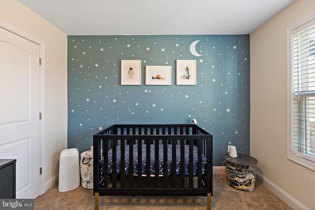 bedroom featuring a nursery area and carpet floors