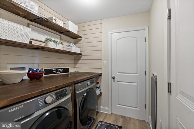 laundry room with washing machine and dryer and light wood-type flooring