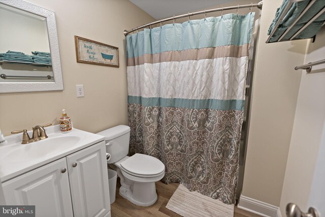 bathroom featuring hardwood / wood-style flooring, vanity, toilet, and curtained shower