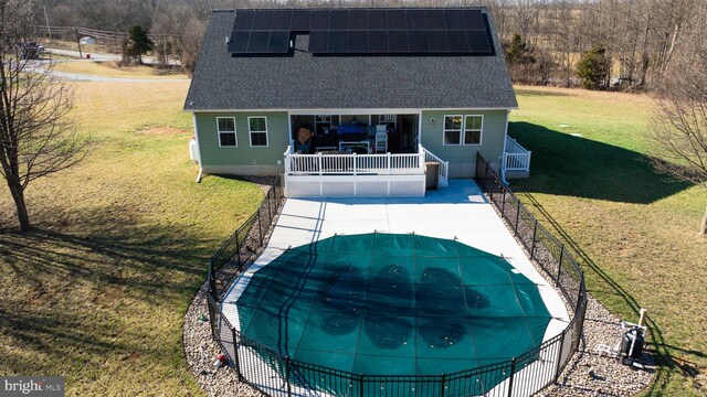 rear view of house with a yard and solar panels