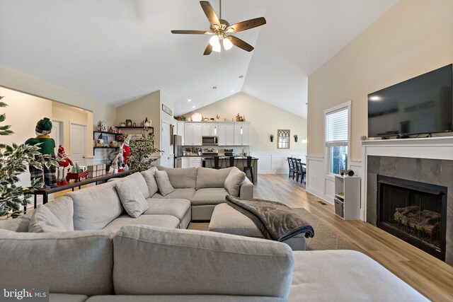 living room with lofted ceiling, a fireplace, light hardwood / wood-style flooring, and ceiling fan