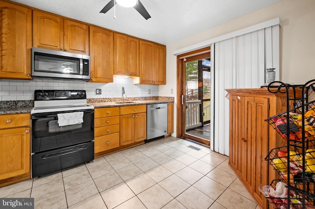 kitchen with appliances with stainless steel finishes, sink, dark stone countertops, and decorative backsplash