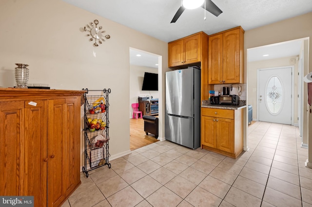 kitchen with backsplash, light tile patterned floors, stainless steel fridge, and ceiling fan