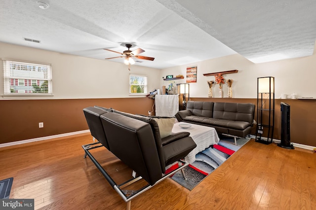 living room with ceiling fan, hardwood / wood-style floors, and a textured ceiling