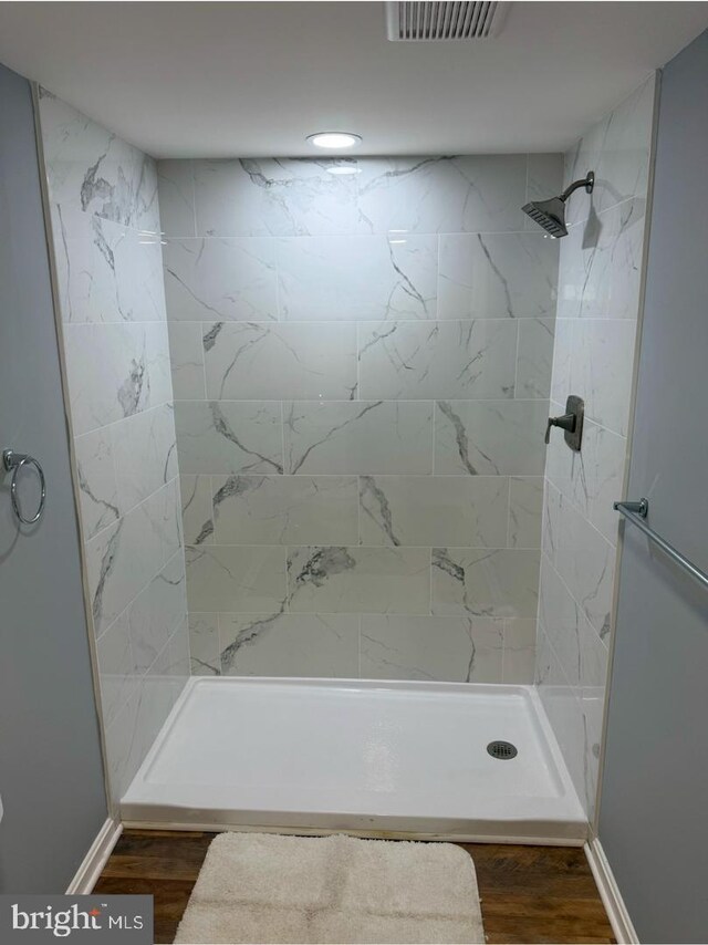 bathroom with hardwood / wood-style flooring and tiled shower