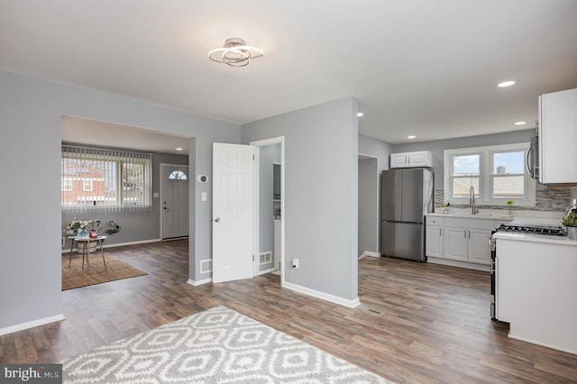 kitchen with stainless steel appliances, white cabinetry, dark wood-type flooring, and tasteful backsplash