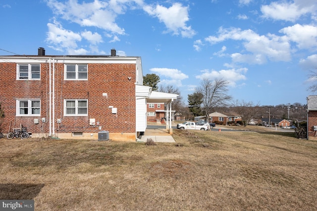 rear view of house featuring cooling unit and a yard