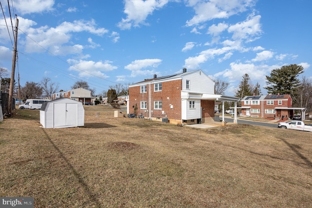 rear view of house featuring a yard and a storage unit