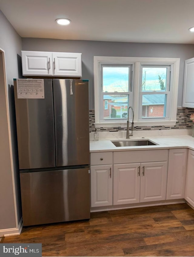 kitchen with sink, white cabinetry, dark hardwood / wood-style floors, stainless steel fridge, and decorative backsplash