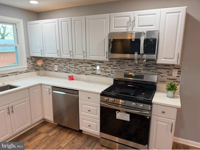 kitchen featuring white cabinetry, backsplash, dark hardwood / wood-style flooring, and appliances with stainless steel finishes