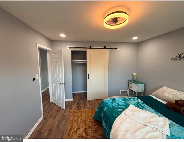 bedroom with a closet, dark hardwood / wood-style floors, and a barn door