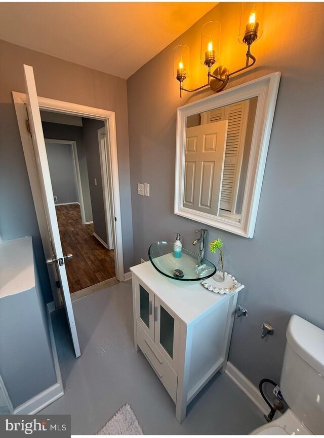 bathroom featuring vanity, concrete floors, a chandelier, and toilet