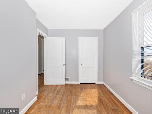 unfurnished bedroom featuring multiple windows and light wood-type flooring