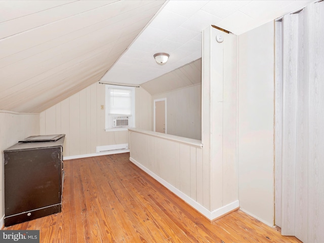 additional living space with hardwood / wood-style flooring, a baseboard radiator, lofted ceiling, and cooling unit