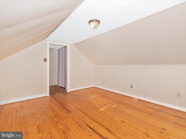 additional living space with hardwood / wood-style flooring and lofted ceiling