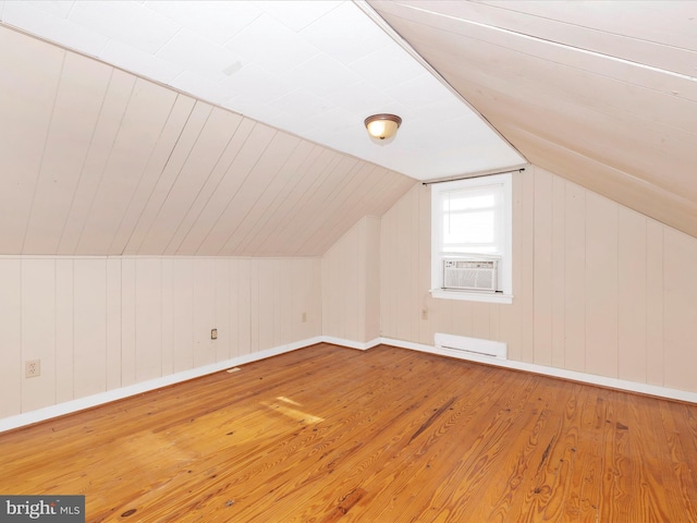 bonus room with cooling unit, lofted ceiling, wood-type flooring, and a baseboard heating unit