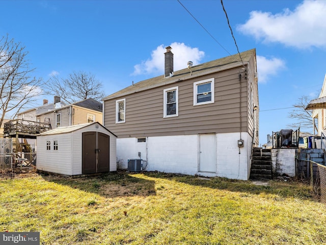 rear view of house with central AC unit, a lawn, and a storage unit