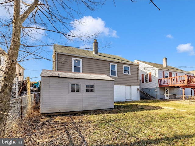 rear view of property with a yard, an outbuilding, and a deck