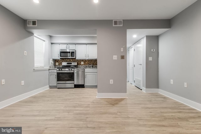 kitchen featuring backsplash, stainless steel appliances, sink, and light wood-type flooring