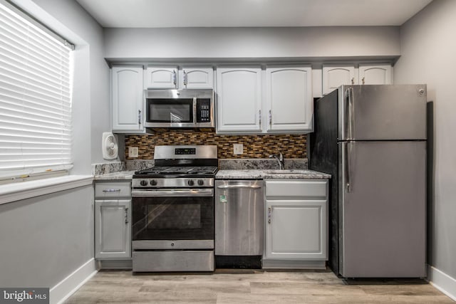 kitchen featuring appliances with stainless steel finishes, sink, light hardwood / wood-style floors, and decorative backsplash