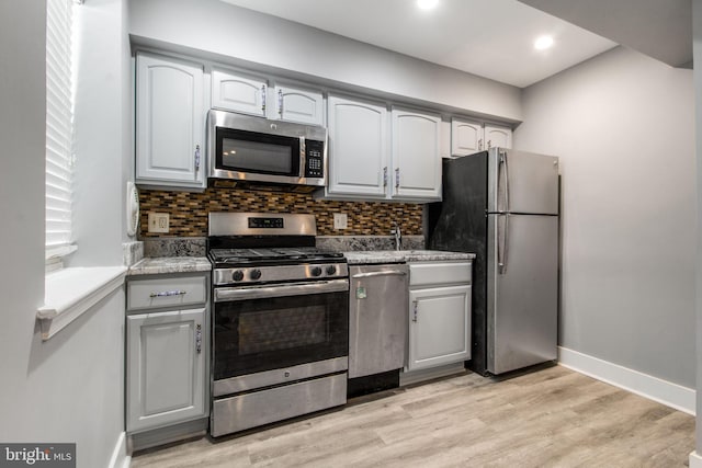 kitchen with stainless steel appliances, light hardwood / wood-style flooring, and decorative backsplash