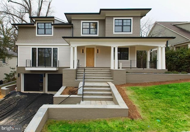 view of front of home with driveway, an attached garage, and a porch