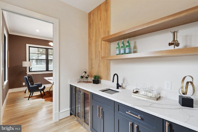 bar featuring wet bar, a sink, light wood-style flooring, and baseboards