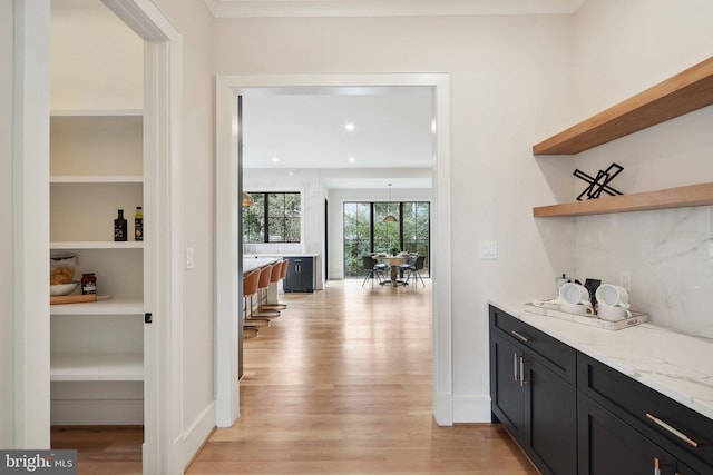 bar featuring light wood-type flooring, backsplash, baseboards, and recessed lighting