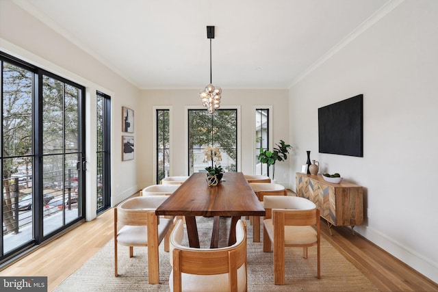 dining area featuring light wood-type flooring, crown molding, and an inviting chandelier