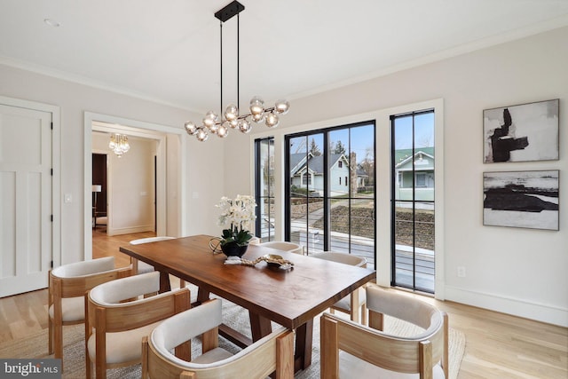 dining room featuring light wood finished floors, baseboards, ornamental molding, and an inviting chandelier