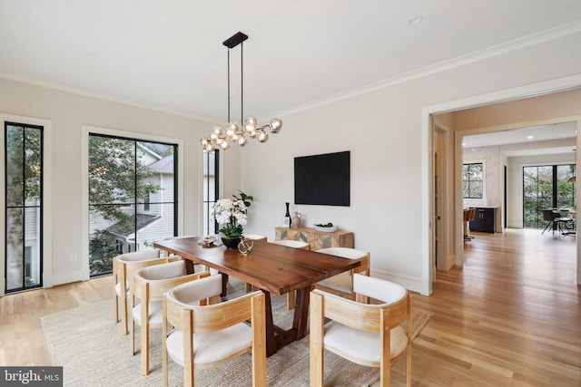 dining area featuring light wood-style flooring, crown molding, baseboards, and a notable chandelier