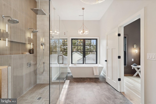 bathroom with a stall shower, a freestanding tub, and a notable chandelier