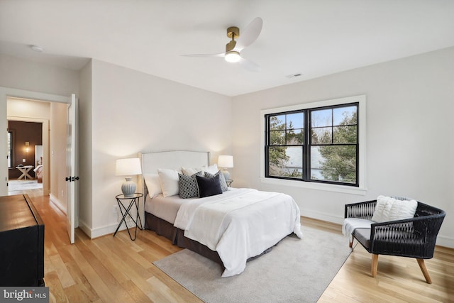 bedroom featuring light wood finished floors, baseboards, visible vents, and a ceiling fan