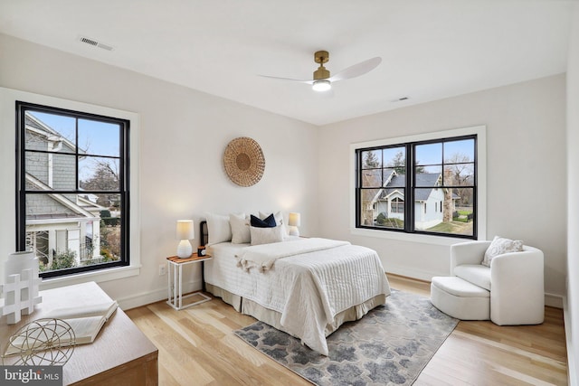 bedroom with multiple windows, visible vents, and light wood-style floors