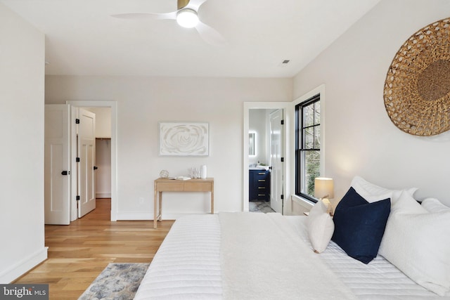 bedroom featuring a ceiling fan, light wood-style flooring, baseboards, and connected bathroom