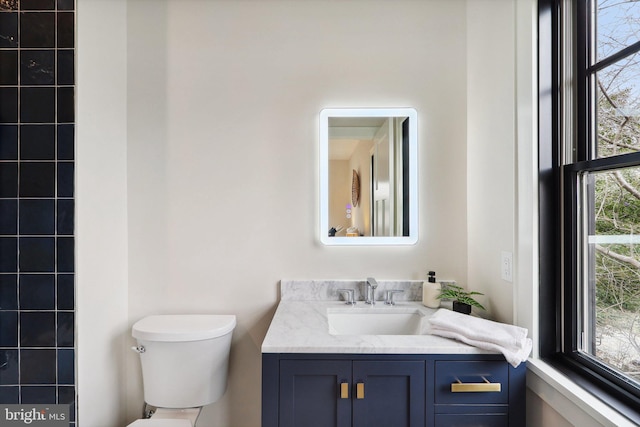 bathroom with a healthy amount of sunlight, vanity, and toilet