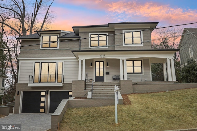 view of front of house featuring a front yard, covered porch, driveway, and an attached garage